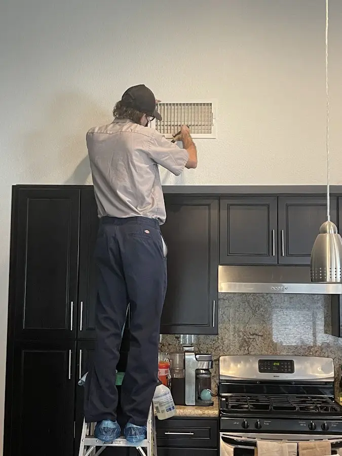 Technician inspecting an air vent during HVAC service in La Palma